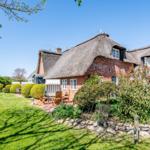 Red brick building with thatched roof and garden area with seating.