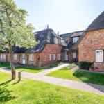 Red brick house with thatched roof and green garden