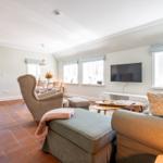 Living and dining area with sofa, armchair, and TV mounted on the wall.