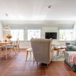 Living and dining area with sofa, armchair, and dining set on terracotta floor.