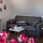 Ein Wohnzimmer mit grauem Sofa, weißem Tisch und Wandbildern.