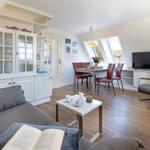 Wohn- und Essbereich mit Dachfenstern, Sofa, TV und Esstisch.