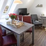 Essbereich mit Tisch, roten Stühlen und großen Dachfenstern. Fernseher und Sessel sind vorhanden.