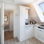 Küche mit weißen Schränken, Waschmaschine und Dachfenster. Tür führt in Schlafzimmer.