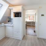 Küche mit Dachfenster, Mikrowelle und Spüle. Durchgang in Wohnbereich mit Holzboden.