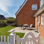 Roter Backsteinbau mit Terrasse, Garten und Gartenzaun.