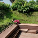 Holzterrasse mit Stufen und Blumenbeete im Garten