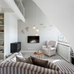 Wohnzimmer mit Sofa, Sessel und Fernseher unter Dachschräge.