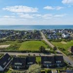 Übersicht über Stranddorf mit Häusern und grünem Feld nahe Meer.