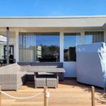 Terrace with seating group, table, and covered grill. Background: windows and house wall.