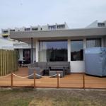 Deck with seating, wooden surface, and covered hot tub.