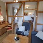 Wohnzimmer mit Holzrahmen, Sofa und Schreibtisch. Blick in Schlafzimmer mit Bett und Kamin.