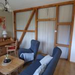 Wohnzimmer mit Holzrahmen, Sofa, Sessel und Schreibtisch.