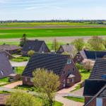 Dorf mit roten Häusern und grünen Feldern unter blauem Himmel.