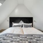 Schlafzimmer mit Dachschrägen, Doppelbett und Dachfenster.