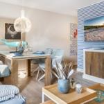 Esszimmer mit Holztisch, Stühlen und Wandbild. Fernseher an gestreifter Wand.