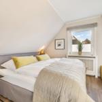 Schlafzimmer mit Dachschräge, Bett, Nachttisch und Fenster mit Blick.