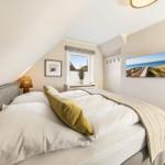 Schlafzimmer mit Dachschräge, Bett, Fenster und Wandbild
