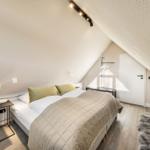 Schlafzimmer mit Dachschrägen, Bett, Nachttisch und Fellteppich.