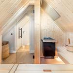 Sauna mit Holzverkleidung, Sitzbänken und Heizung. Glaswand trennt den Raum.