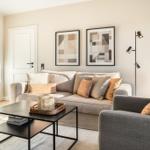 Wohnzimmer mit Sofa, Sessel, Tisch und Wandbildern.