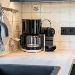 Küchenzeile mit Kaffeemaschine und Kaffeemaschine auf Holzoberfläche.