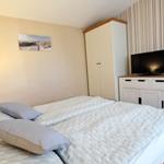 Schlafzimmer mit Doppelbett, Kleiderschrank und TV-Möbel.