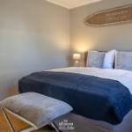 Schlafzimmer mit Bett, Kissen, Nachttisch und Wanddekoration.