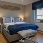 Schlafzimmer mit Bett, Nachttischen und Fenster. Wanddekoration mit Koordinaten.
