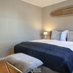 Schlafzimmer mit Bett, Spiegel und Wanddekoration.