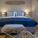 Schlafzimmer mit Bett, Nachttischen und Wanddekoration.