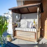 Holzschuppen mit Sitzbank, Kissen und Flasche auf Terrasse.