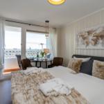 Schlafzimmer mit Balkon, Bett, Kissen und Weltkarte an der Wand.