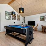Raum mit Billardtisch, TV, Schreibtisch und Holzdecke.