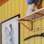 Wandregal aus Bambus mit Vase und Kleiderhaken an gelber Wand