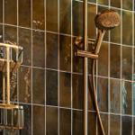 Dusche mit goldfarbenem Duschsystem und farbigen Fliesen