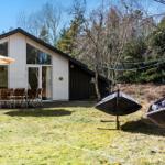 Moderne Ferienhaus mit Terrasse, Garten und Gartenmöbeln. Hintergrund: Wald.