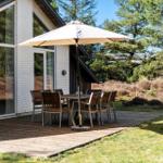 Terrasse mit Tisch, Stühlen und Sonnenschirm neben modernem Haus.