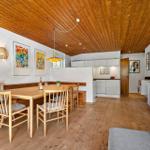 Essbereich mit Holztisch, Stühlen und Küchenbereich im Hintergrund.