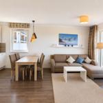 Wohnzimmer mit Sofa, Sessel und Balkonblick