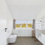 Badezimmer mit Duschbereich und Fensterblick auf die Landschaft.