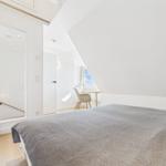 Schlafzimmer mit Bett, Schreibtisch und Fenster. Dachschrägen und helle Wände.