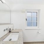 Badezimmer mit Waschbecken, Spiegel und Fenster