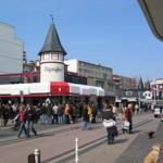 Market square with people and a tower building with an ice cream shop.
