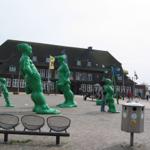 Large green sculptures in the station square with seating and flags.