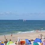 Beach with colorful tents, people, and boats in the sea.