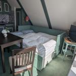 Bedroom with bed, dining table, and kitchen area under sloped ceilings.