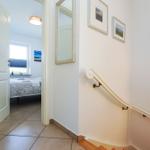 Hausflur mit Treppenhaus und Blick in Schlafzimmer mit Bett und Fenster.