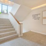 Hausflur mit Treppe, Wandtafel und Kunstwerk. Boden und Stufen aus Terrazzo.
