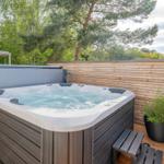 Hochwertige Whirlpool-Terrasse mit Holzgeländer und Pflanze im Hintergrund.